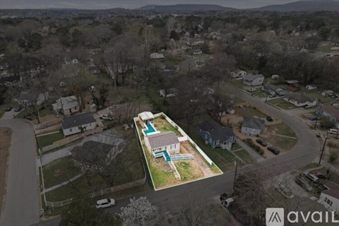 An aerial view of a neighborhood with a house that has a pool in the backyard.