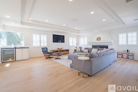 A spacious living room with a grey sofa and a television mounted on the wall.