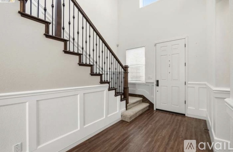 A staircase with a black railing and wooden steps leads to a white door.