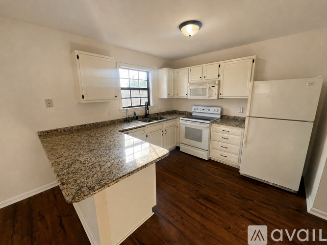 A kitchen with granite countertops and white appliances.