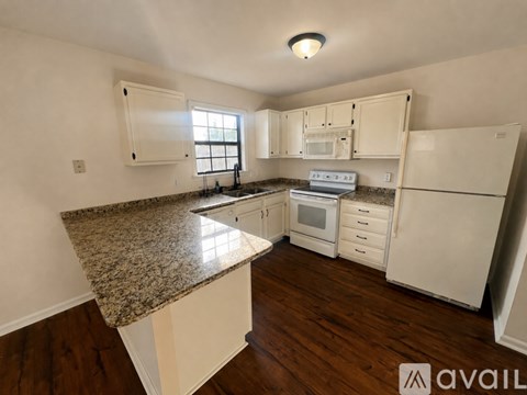 A kitchen with granite countertops and white appliances.