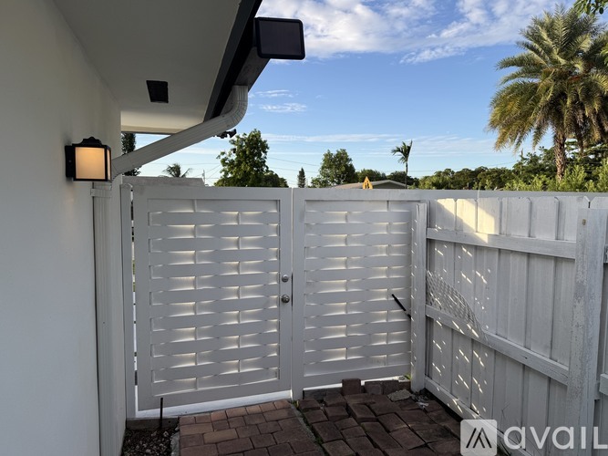 A white gate with horizontal slats is closed.