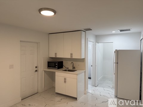A kitchen with white cabinets and a marble floor.