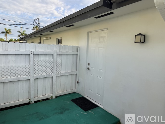 A white fence and door with a green mat in front.