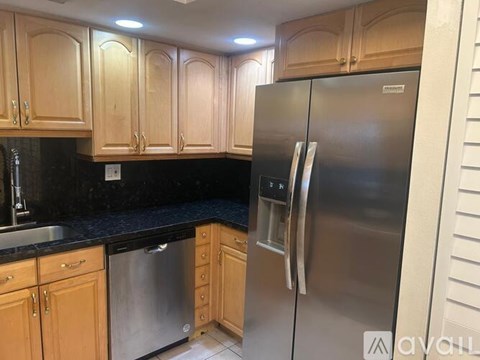 A kitchen with wooden cabinets and a stainless steel refrigerator.
