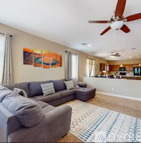 A living room with a grey couch and a painting on the wall.