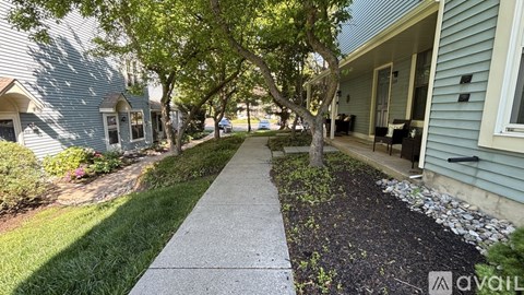 A residential street with houses on both sides and a sidewalk in the foreground.