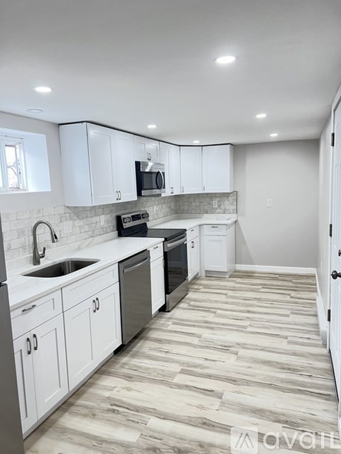A kitchen with white cabinets and a wooden floor.