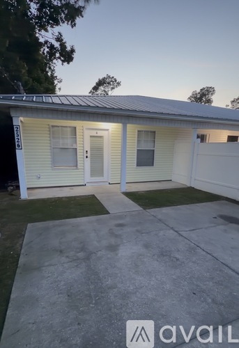 A small house with a white fence and a concrete driveway.