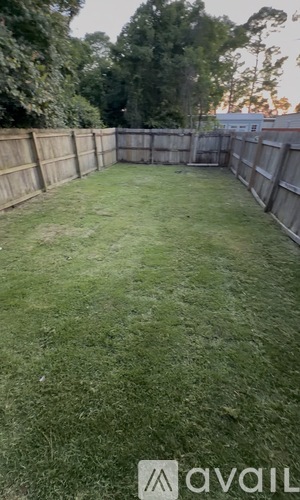 A backyard with a wooden fence and green grass.