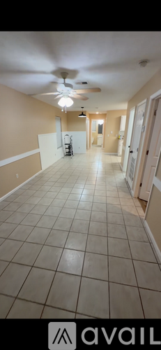 A long hallway with a fan and tiled floors.