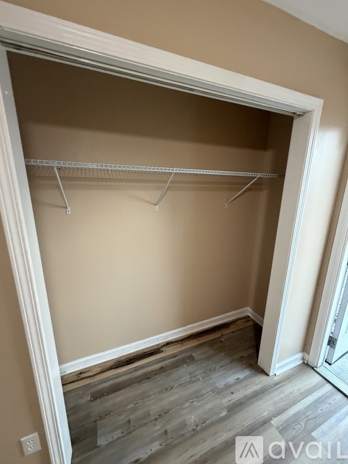 A white closet with a grey floor and a white door.