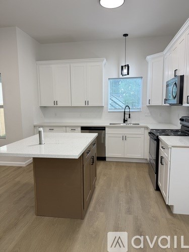 A kitchen with white cabinets and a wooden floor.