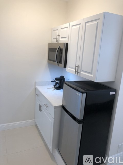 A kitchen with white cabinets and a black fridge.