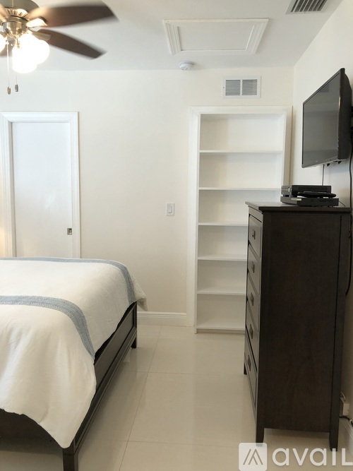 A bedroom with a bed, a television, and a fan.