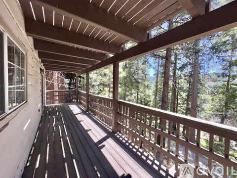 A wooden deck with railings and a view of trees.