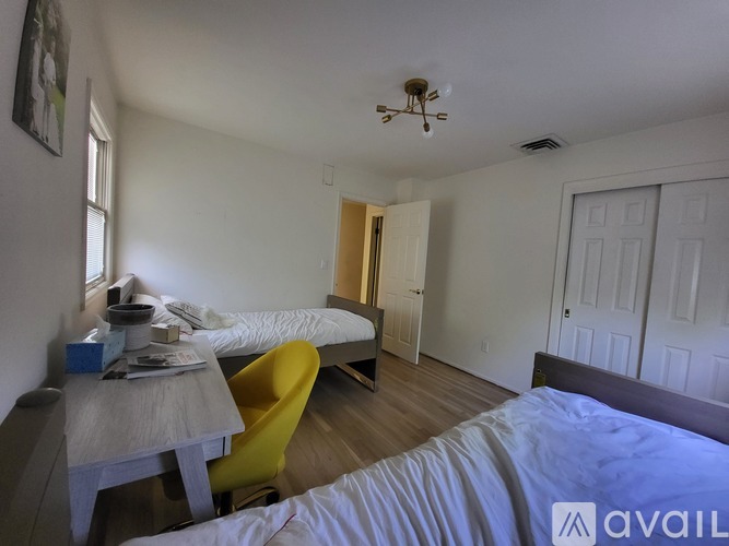A room with a bed, a table, and a yellow chair.
