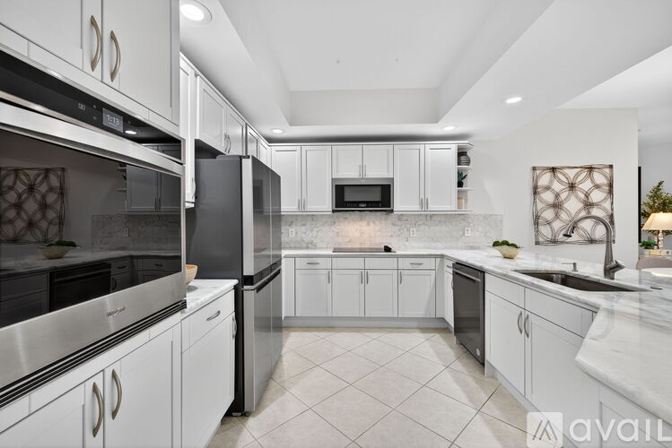 A modern kitchen with white cabinets and stainless steel appliances.