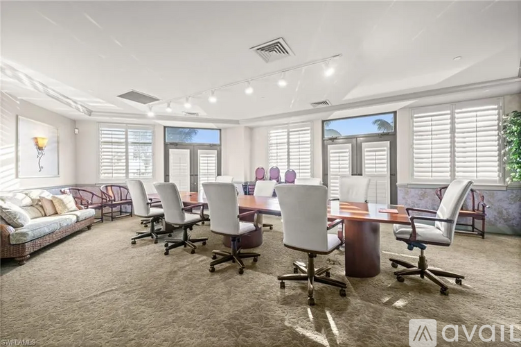 A conference room with a long table and chairs, a couch, and a plant in the corner.