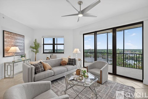 A living room with a grey couch and a large window overlooking the water.