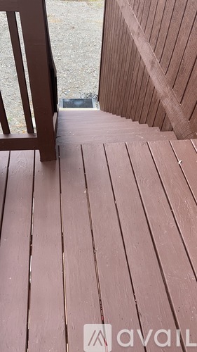 A wooden deck with a chair and steps leading to a door.