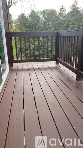 A wooden deck with a railing and trees in the background.
