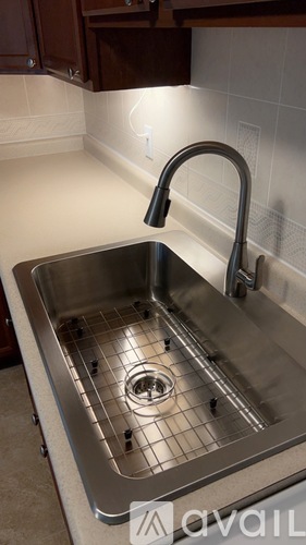 A kitchen sink with a chrome faucet and a drain in the middle.