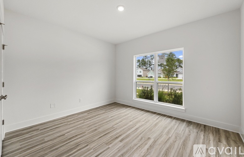 A room with a window showing a view of a house and trees.