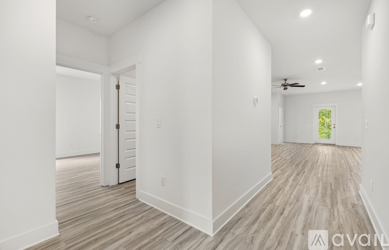 A spacious room with wooden flooring and white walls.