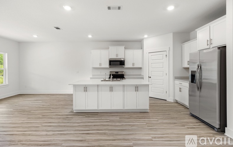 A kitchen with white cabinets and a wooden floor.