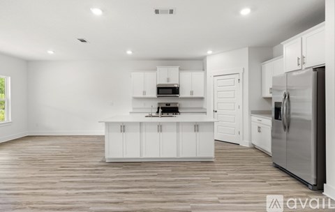 A kitchen with white cabinets and a wooden floor.