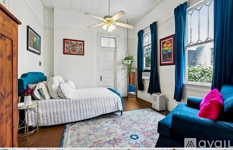 A bedroom with a bed, a couch, and a ceiling fan.