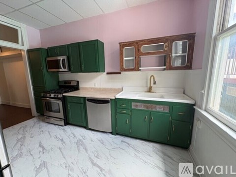 A kitchen with green cabinets and a white marble countertop.