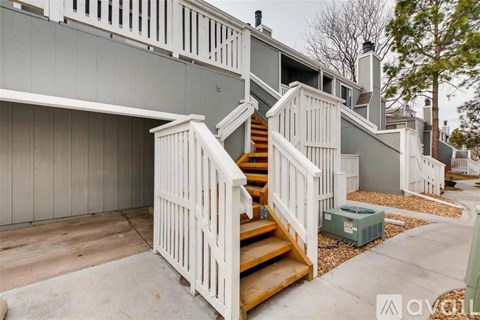 A white staircase with a wooden handrail leads up to a building.