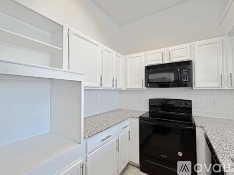 A kitchen with white cabinets and a black oven.