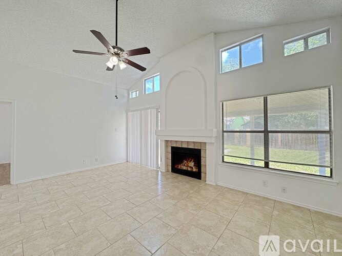 A living room with a fireplace and a ceiling fan.