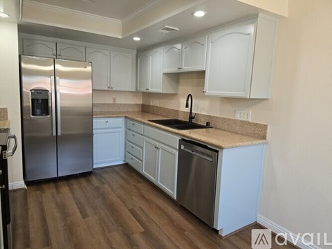 A kitchen with white cabinets and a stainless steel refrigerator.