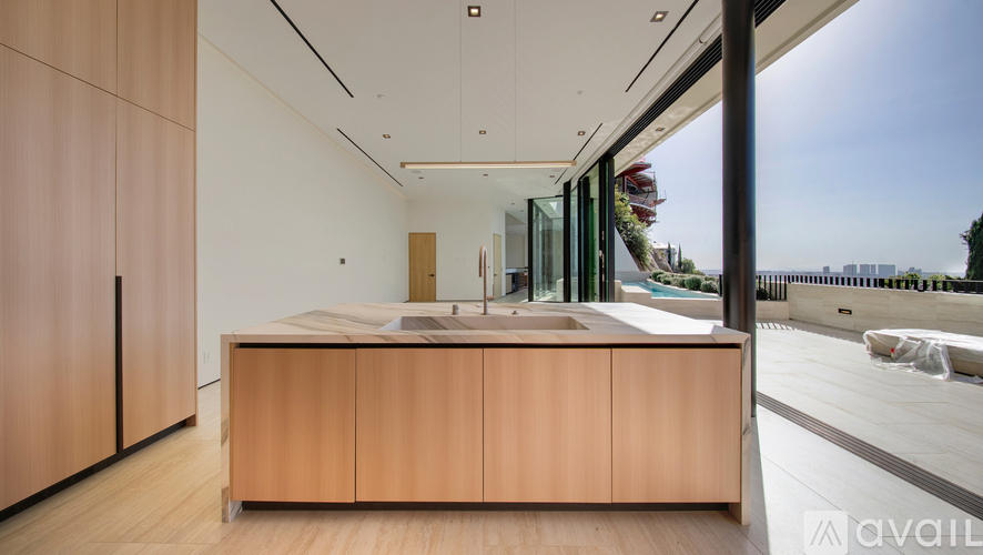 A modern kitchen with wooden cabinets and a large window overlooking the city.