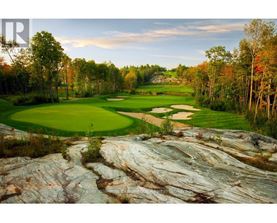 A golf course with a large rock formation in the foreground.