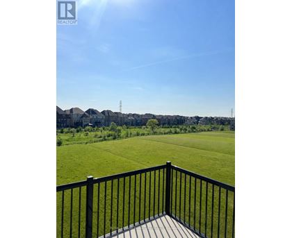 A black railing overlooks a green field.