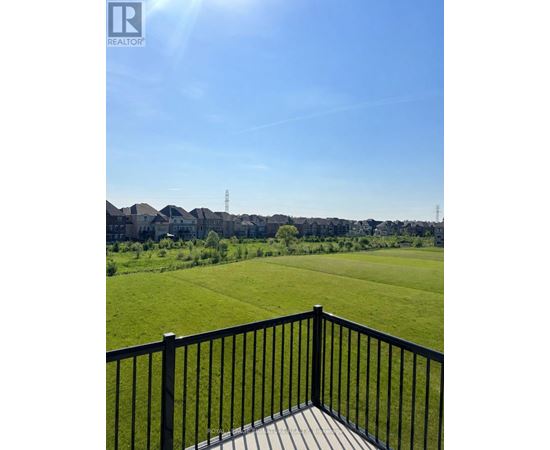 A black railing overlooks a green field.