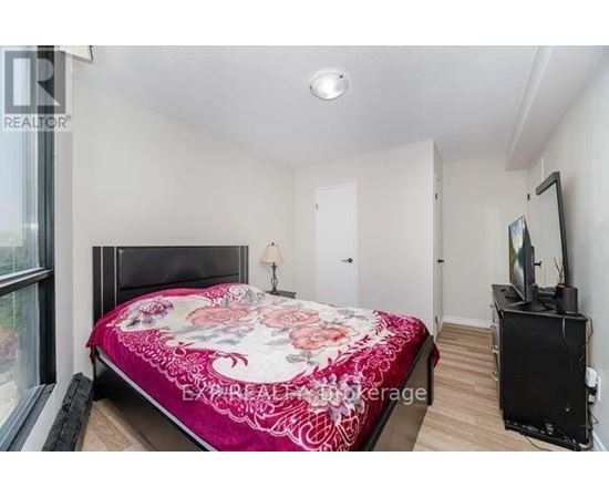 Bedroom with a bed, a television, and a window.