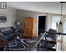 A living room with a grey couch, a wooden cabinet, and a glass table.