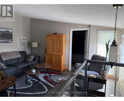 A living room with a grey couch, a wooden cabinet, and a glass table.