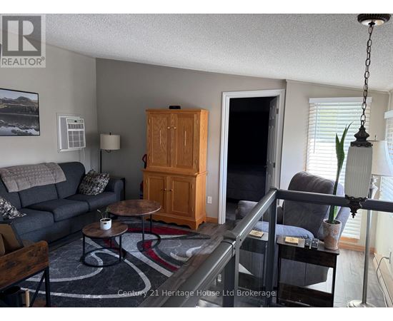 A living room with a grey couch, a wooden cabinet, and a glass table.