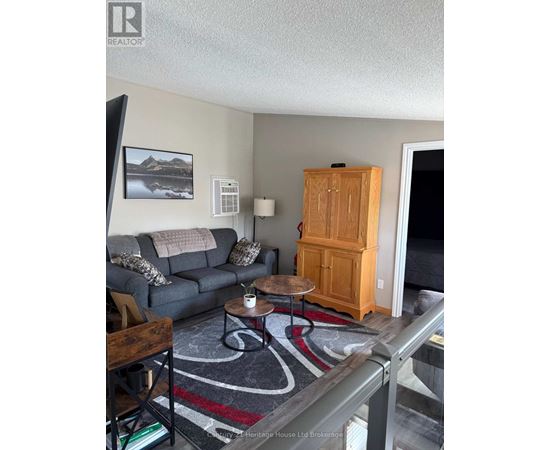 A living room with a grey couch, a wooden cabinet, and a rug.