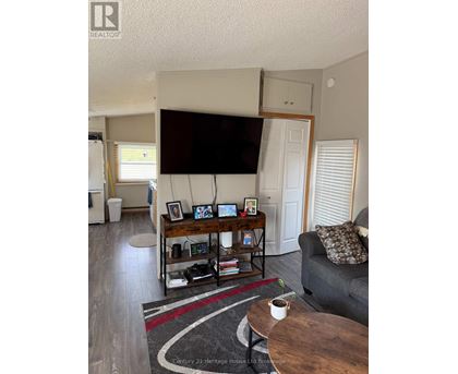 A living room with a grey couch, a coffee table, and a television mounted on the wall.