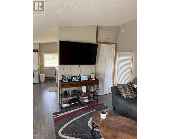 A living room with a grey couch, a coffee table, and a television mounted on the wall.