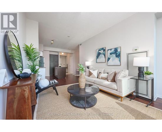 A living room with a white couch, a coffee table, and a painting on the wall.