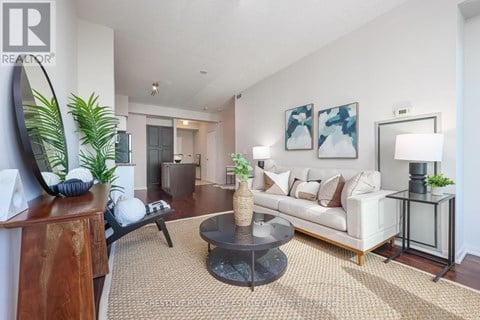 A living room with a white couch, a coffee table, and a painting on the wall.